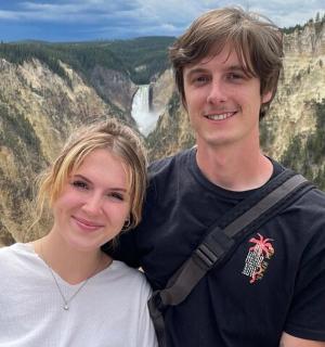 a man and a woman standing in front of a mountain