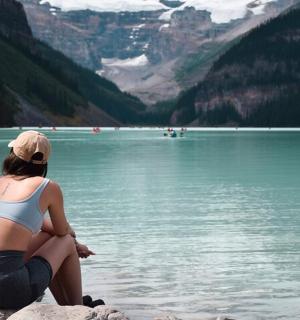 一名女子坐在水边的岩石上