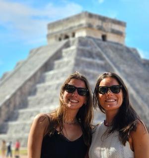 two women are standing in front of a pyramid