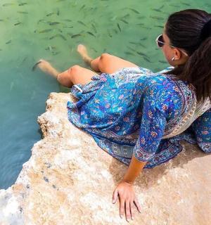 a woman sitting on a rock near the water