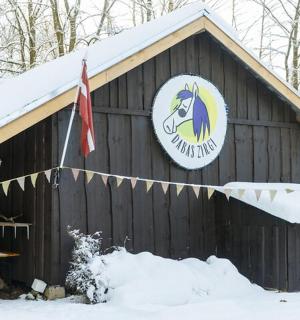 雪地里有一座黑色谷仓，上面挂着一块牌子