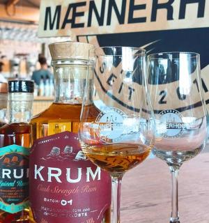 two wine glasses sitting on a table with bottles of alcohol