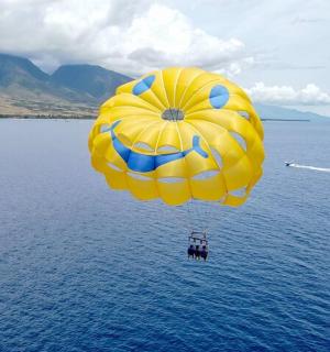 一顶黄色和蓝色的降落伞在水面上飞翔
