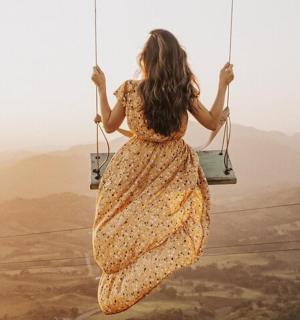a woman in a dress sitting on a swing