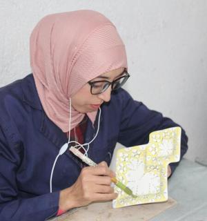 一位戴着粉色头巾的女士正在剪纸