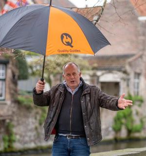 Starší muž držící deštník v dešti