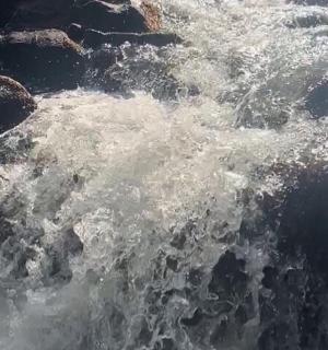 vlna ve vodě vedle skal