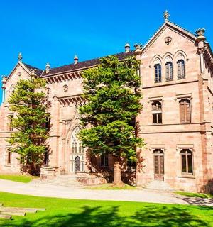 ein altes Steingebäude mit einem Baum davor