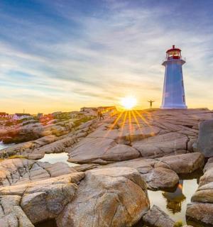 a lighthouse on a rocky shore with the setting sun