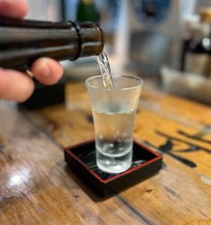 一个人把饮料倒进桌上的玻璃杯里