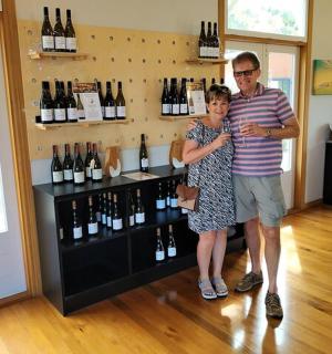 a man and a woman standing next to a display of wine bottles