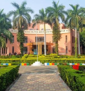 a pink building with palm trees in front of a garden
