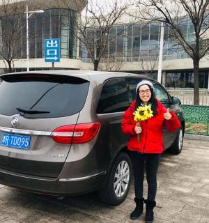 一位手持向日葵的女士站在汽车旁边