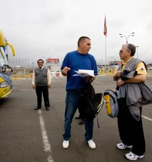 two men standing in a parking lot next to a bus