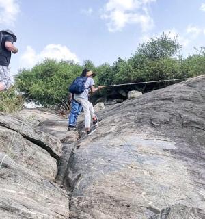 dva lidé chodící po skalách s lanem