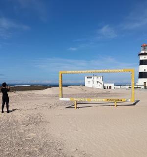 a person standing on a beach with a lighthouse