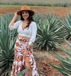 a woman wearing a hat standing in a pineapple plantation