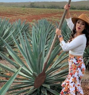 a woman in a hat standing next to a plant