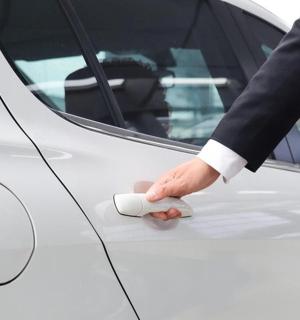 一名西装革履的人正在解锁一辆白色汽车