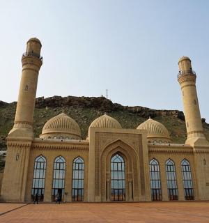 一座有三座塔楼的建筑,背景是一座小山