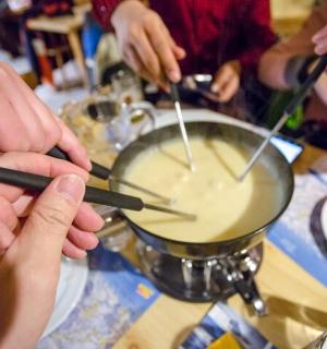 a group of people stirring a pot with chopsticks