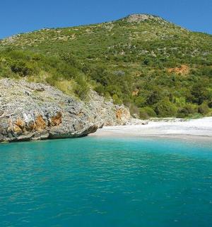 pláž s modrou vodou a horou v pozadí