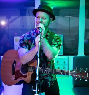 muž držící kytaru a zpívající do mikrofonu