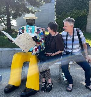 a man and a woman sitting on a bench with a statue