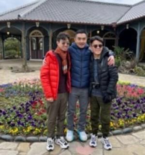 three people standing in front of a flower clock