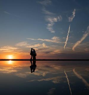 一个人站在水面上，欣赏日落