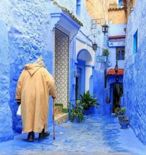 穿着雨衣的人走在蓝色的小巷里