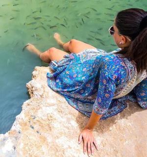 a woman sitting on a rock by the water