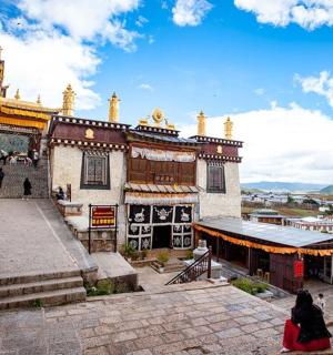 一名女子坐在建筑物前的地面上