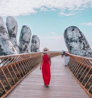 一位身穿红裙的女子,用两只大手走在桥上