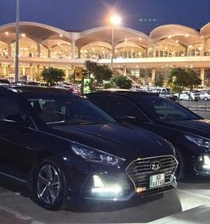 dvě černá auta zaparkovaná na parkovišti před budovou