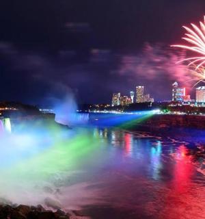 a firework display over a waterfall at night with a city