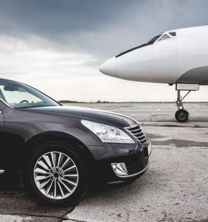 a black car is parked next to an airplane