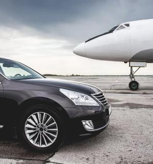 a black car is parked next to an airplane