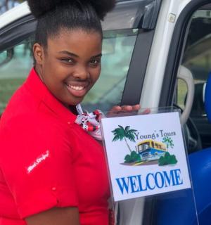 一名女子在汽车前举着欢迎牌