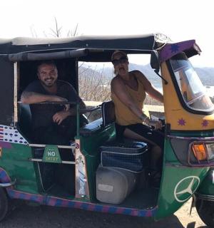 two men sitting in the back of a small golf cart