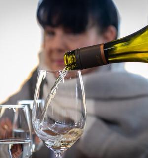 a person pouring a bottle of wine into two wine glasses