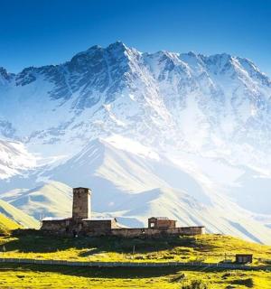 一座白雪覆盖的山峰，田野上有一栋建筑