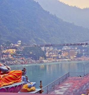a statue of a woman sitting on a ledge overlooking a river