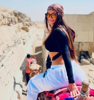 一名女子坐在沙漠中的骆驼上