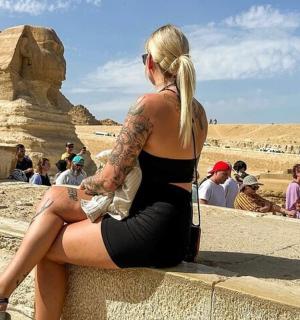 一位女士坐在墙上，看着金字塔