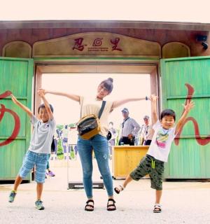 a woman and two children jumping in front of a building