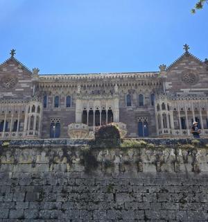 ein großes Gebäude hinter einer Backsteinmauer mit einer Burg