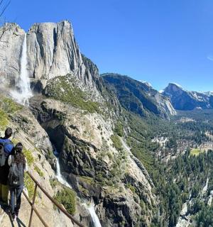 Pár lidí stojících na útesu a dívajících se na vodopád