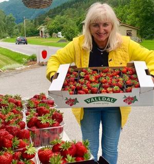 a woman is holding a box of strawberries