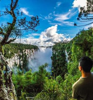 一名男子站在山上，看着瀑布